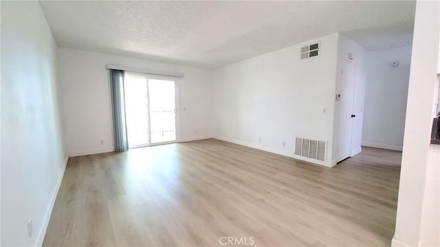 unfurnished room with light wood-type flooring and a textured ceiling