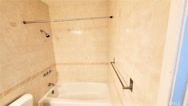 bathroom with tiled shower / bath combo and toilet