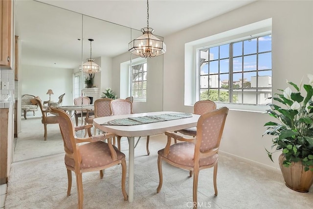 dining space featuring light carpet and a chandelier