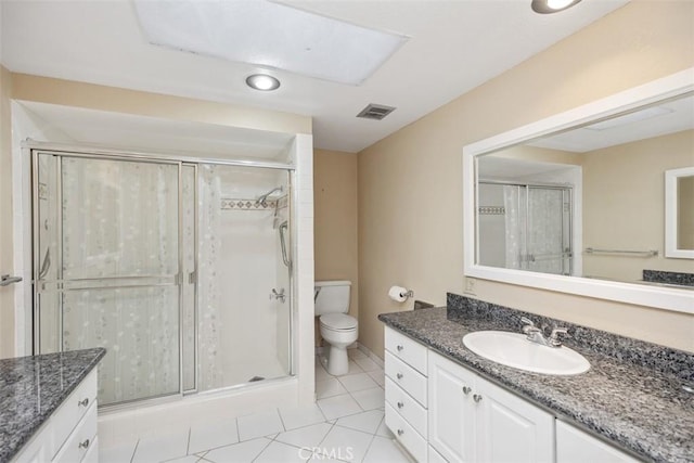 bathroom featuring toilet, vanity, tile patterned floors, and a shower with shower door