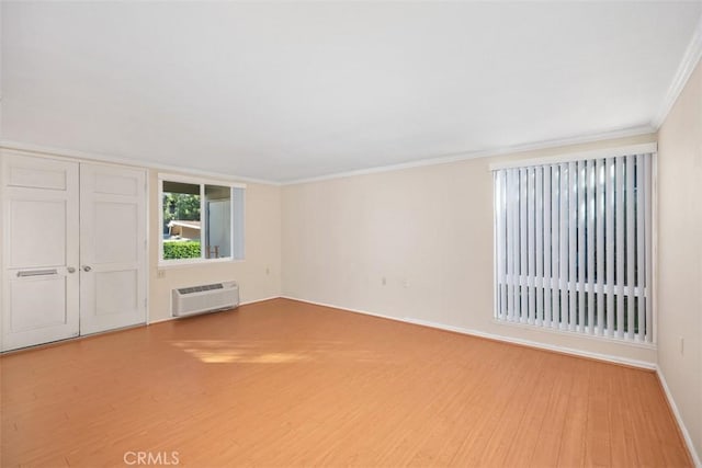 interior space featuring a wall mounted air conditioner, wood-type flooring, and ornamental molding