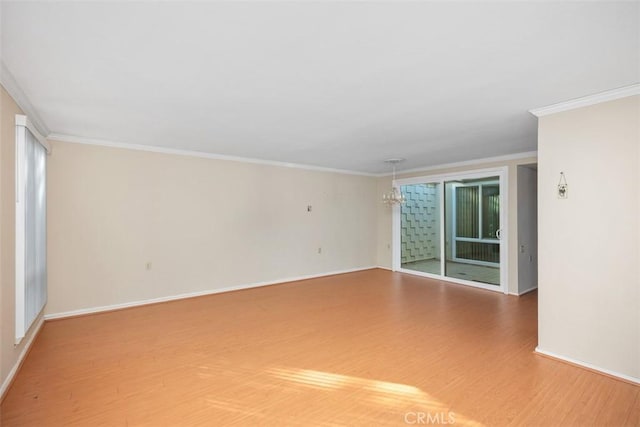 spare room with hardwood / wood-style flooring, ornamental molding, and an inviting chandelier