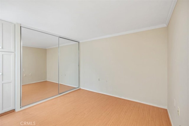 unfurnished bedroom featuring crown molding, a closet, and hardwood / wood-style flooring