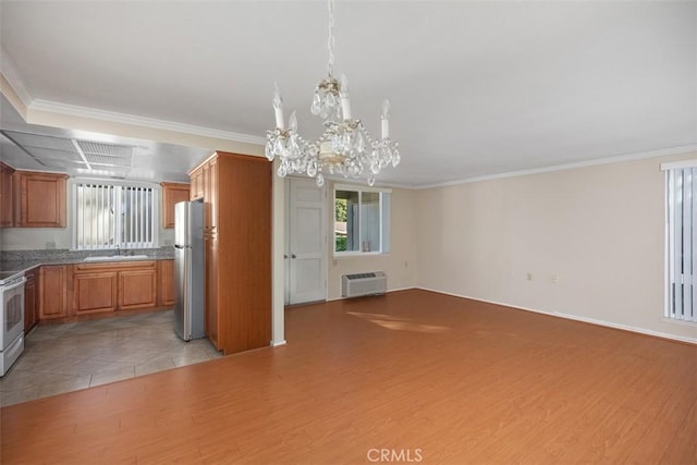 kitchen with a wall mounted air conditioner, sink, hanging light fixtures, stainless steel fridge, and light hardwood / wood-style floors