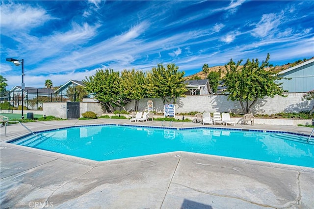 community pool with a patio and fence