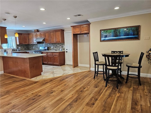 11881 Old Fashion Way, Garden Grove, CA 92840 - kitchen featuring crown molding, stainless steel gas stove, under cabinet range hood, light countertops, and a peninsula