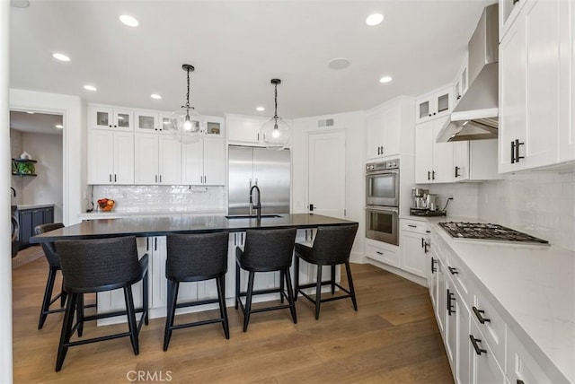 kitchen featuring white cabinets, wall chimney exhaust hood, and stainless steel appliances