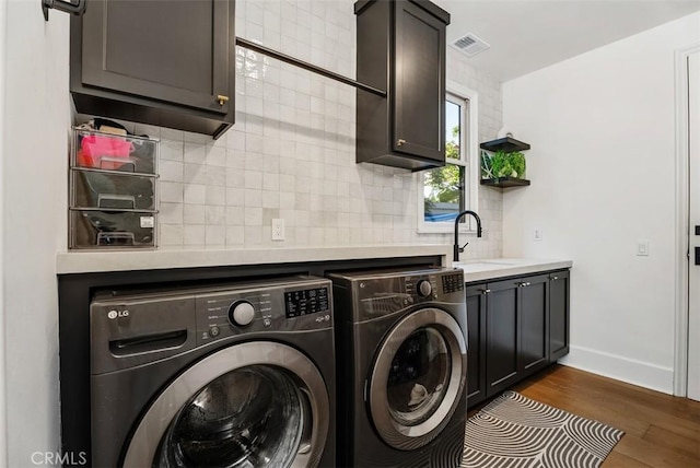 laundry area featuring cabinets, independent washer and dryer, dark wood-type flooring, and sink