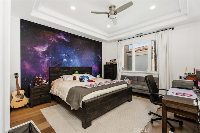 bedroom featuring a tray ceiling, ceiling fan, and hardwood / wood-style flooring