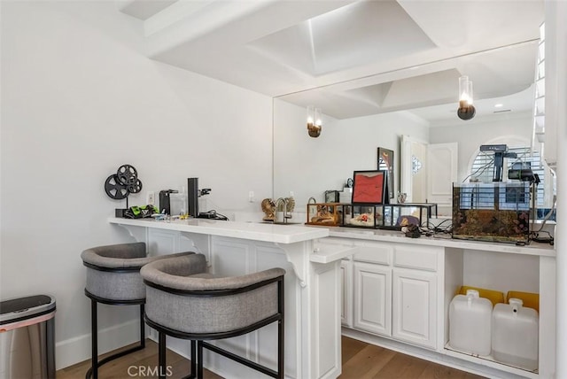 kitchen featuring white cabinets, hanging light fixtures, dark hardwood / wood-style floors, a kitchen bar, and kitchen peninsula