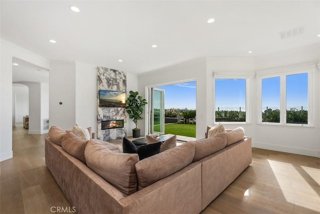 living room with light hardwood / wood-style flooring, crown molding, and a premium fireplace