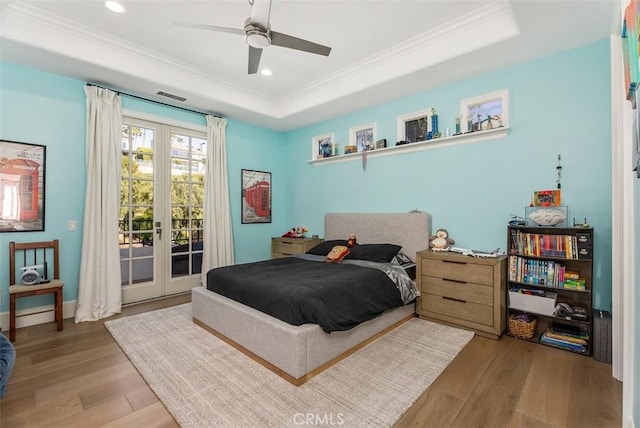 bedroom featuring access to outside, french doors, a raised ceiling, ceiling fan, and light hardwood / wood-style floors