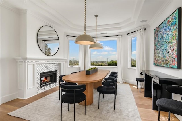 dining space featuring light hardwood / wood-style floors, ornamental molding, a fireplace, and a wealth of natural light