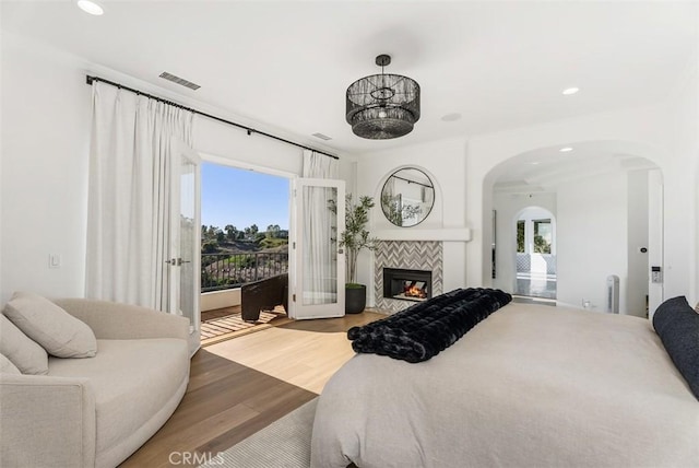 bedroom featuring access to exterior, hardwood / wood-style floors, multiple windows, and a tiled fireplace