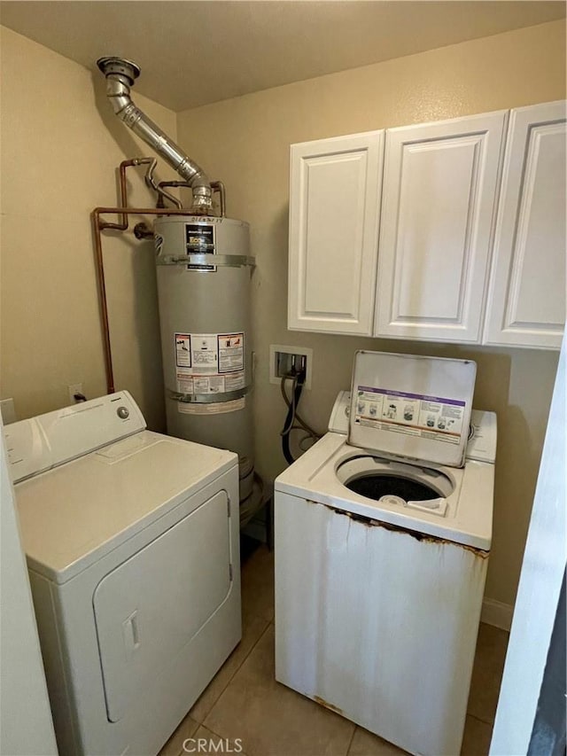 clothes washing area featuring light tile patterned flooring, secured water heater, separate washer and dryer, and cabinets