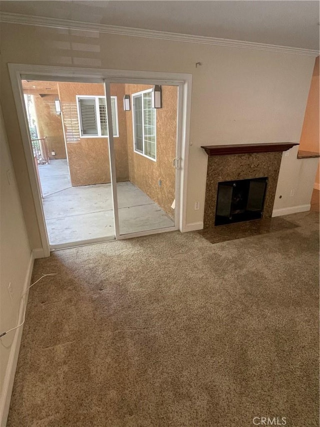 unfurnished living room featuring a high end fireplace, ornamental molding, and carpet