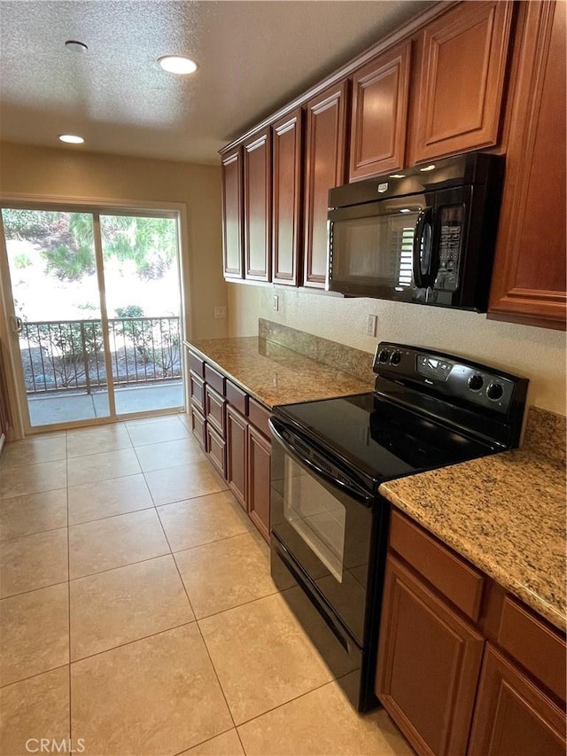 kitchen with light tile patterned floors, a textured ceiling, black appliances, and light stone counters