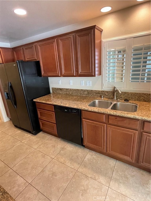 kitchen featuring black appliances, light stone countertops, light tile patterned flooring, and sink