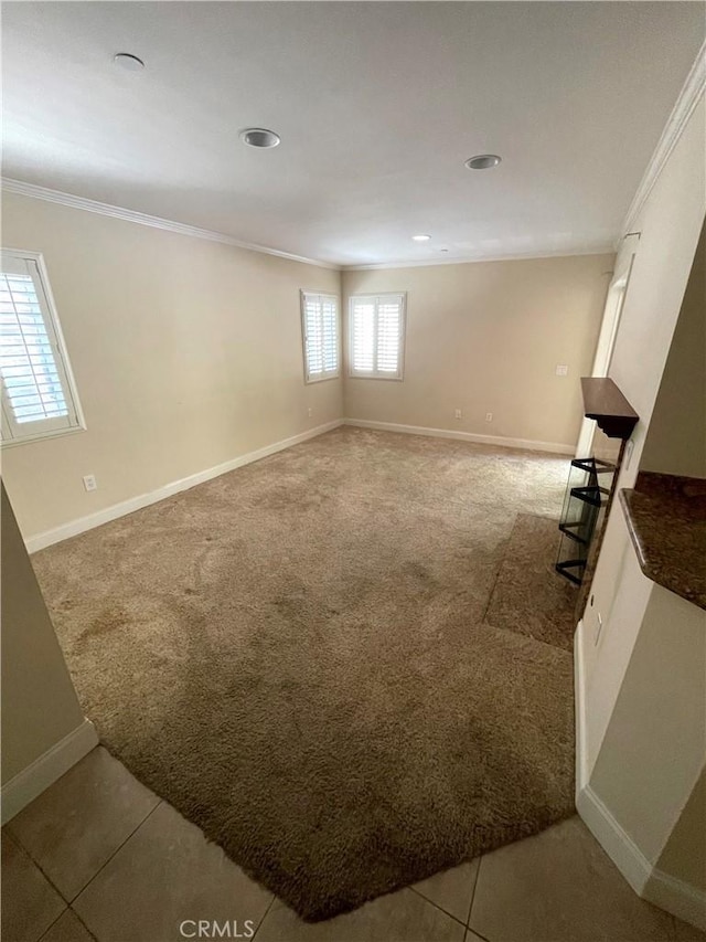 interior space featuring carpet floors, baseboards, crown molding, and tile patterned floors