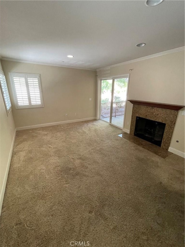 unfurnished living room with baseboards, a premium fireplace, ornamental molding, and carpet flooring