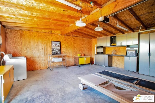 interior space featuring lofted ceiling with beams, wood walls, and separate washer and dryer