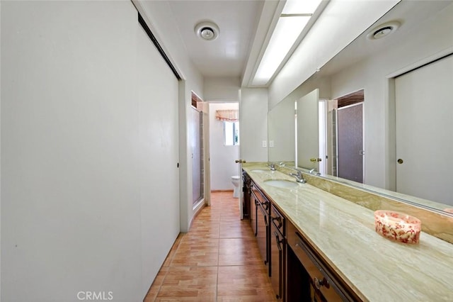 bathroom with a shower with door, vanity, and toilet