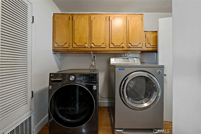 clothes washing area featuring cabinets, washer and dryer, and dark wood-type flooring