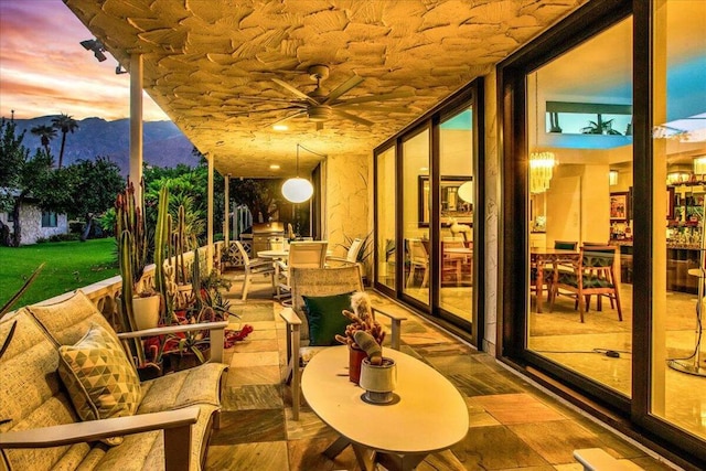 patio terrace at dusk featuring a mountain view and ceiling fan