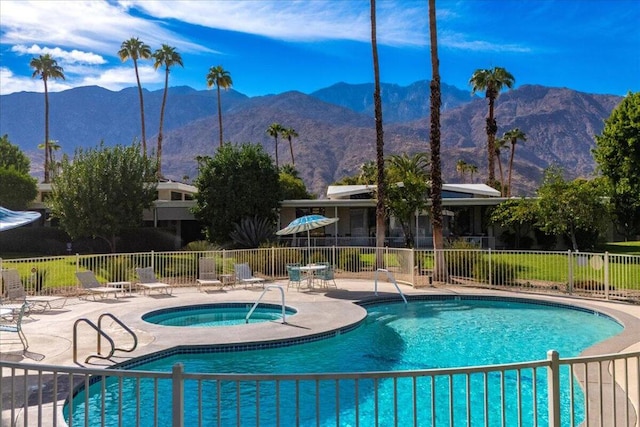 view of swimming pool featuring a hot tub, a mountain view, and a patio