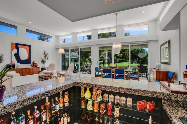 interior space with stone counters, a towering ceiling, and an inviting chandelier