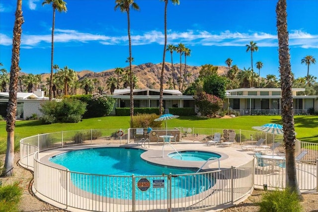 view of pool featuring a hot tub, a mountain view, a yard, and a patio