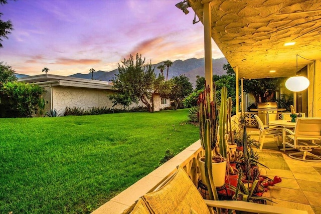 yard at dusk with a patio area and a mountain view