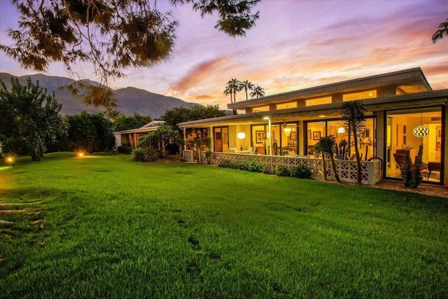 back house at dusk featuring a yard and a mountain view