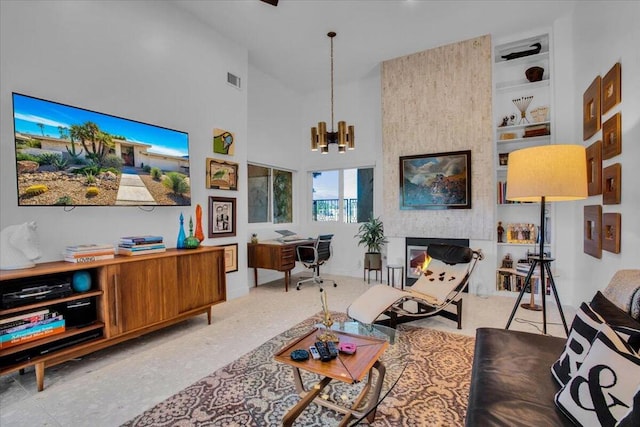 living room with a notable chandelier, a towering ceiling, a fireplace, and built in shelves