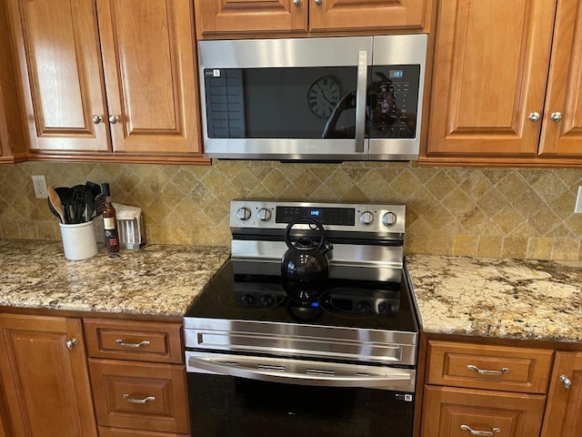 kitchen featuring backsplash, stainless steel appliances, and light stone counters