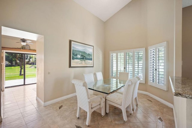 tiled dining space with ceiling fan and high vaulted ceiling