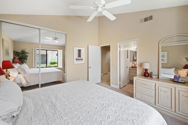 carpeted bedroom featuring ceiling fan, lofted ceiling, ensuite bathroom, and a closet