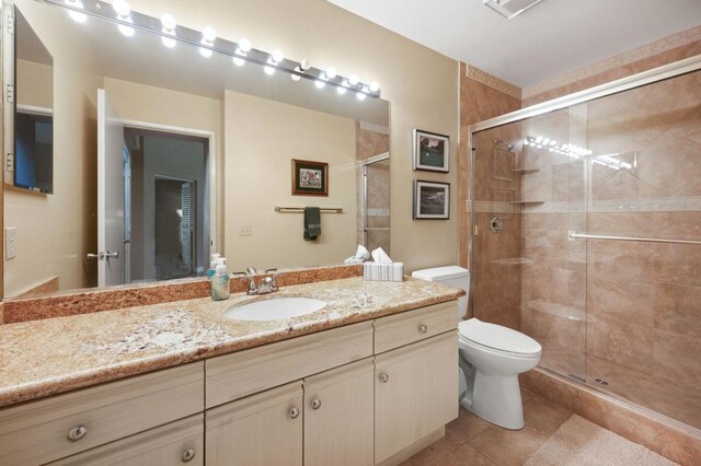 bathroom with tile patterned flooring, vanity, an enclosed shower, and toilet