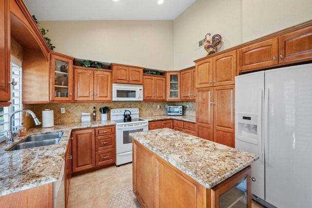 kitchen with decorative backsplash, light stone countertops, sink, and white appliances