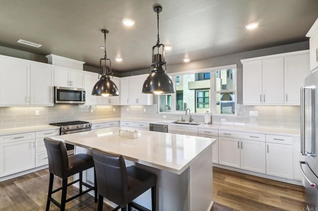 kitchen featuring a center island, appliances with stainless steel finishes, dark hardwood / wood-style floors, and white cabinets