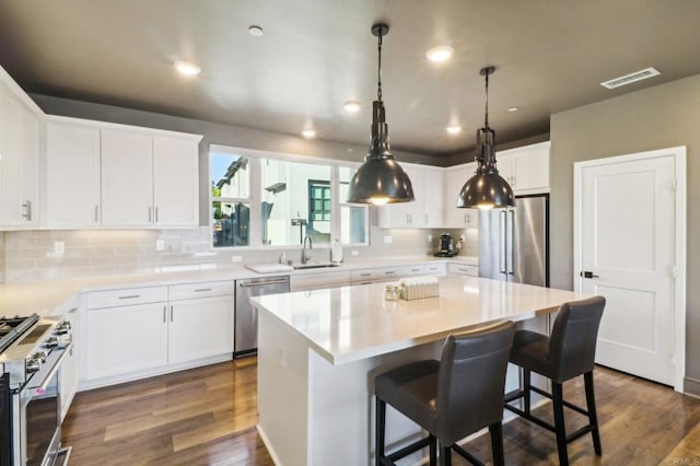 kitchen with a kitchen island, decorative backsplash, dark hardwood / wood-style floors, high end appliances, and white cabinetry