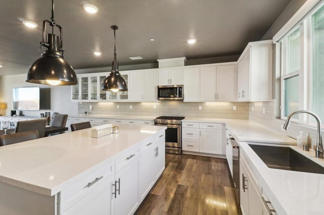 kitchen featuring white cabinets, tasteful backsplash, a kitchen island, sink, and stainless steel appliances