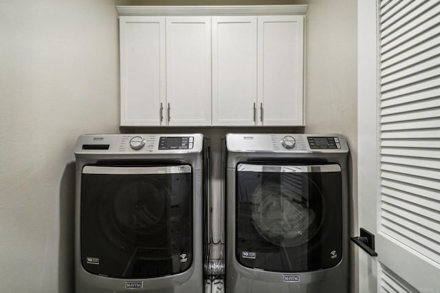 clothes washing area with cabinet space and washing machine and dryer