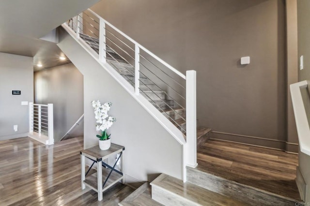 staircase featuring baseboards and wood finished floors