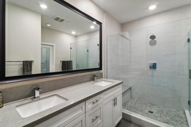 bathroom with double vanity, visible vents, a stall shower, and a sink