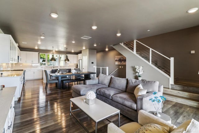 living room with recessed lighting, visible vents, dark wood finished floors, and stairs