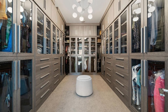 walk in closet with a chandelier and light carpet