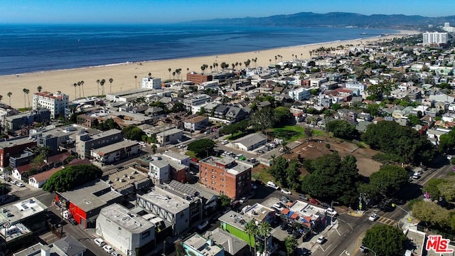 drone / aerial view with a water and mountain view and a view of the beach