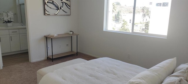 bedroom featuring dark colored carpet, sink, and ensuite bath