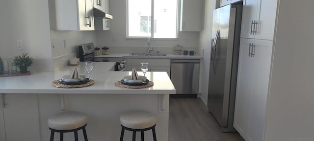 kitchen with a kitchen breakfast bar, white cabinetry, and stainless steel appliances